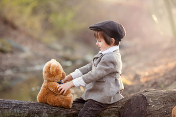Adorable little boy with his teddy bear friend in the park
