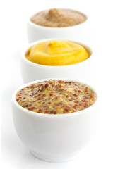 Three kinds of mustard in a line in perspective. Isolated.