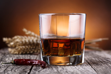 Glass of whiskey with ice and wheat on a wooden table.