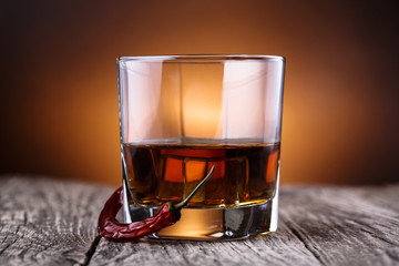 Whiskey with chili on a wooden table.