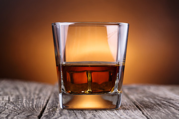Glass of whiskey and ice on a wooden table.