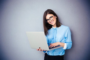 Smiling businesswoman standing and using laptop