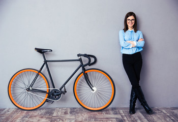 Cheerful young businesswoman standing near bicycle