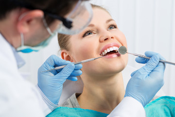 Male dentist examining patient teeth before oral operation