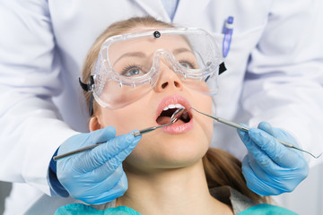 Professional dentist curing infected molar of young woman