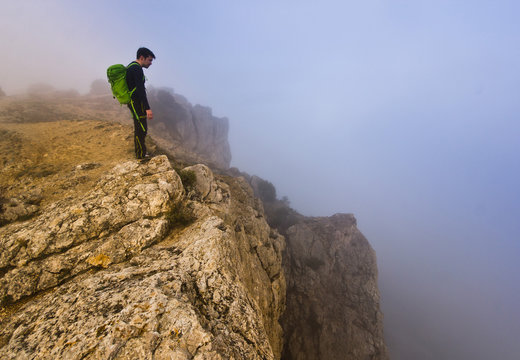 man standing on a cliff in foggy weather