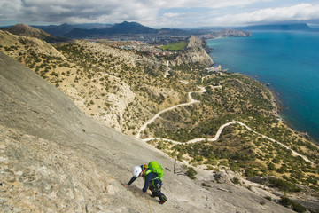 rock climber climbs mountain with sea on background