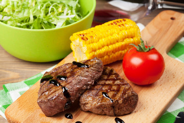 Steak with grilled corn, salad and red wine