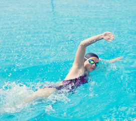 Woman in goggles swimming front crawl style