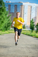 Sporty man jogging in city street park. Outdoor fitness.
