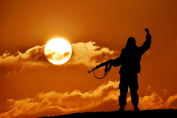 Silhouette of soldier officer with weapons at sunset