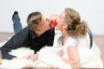 Paar liegt auf dem Boden und albert mit Apfel