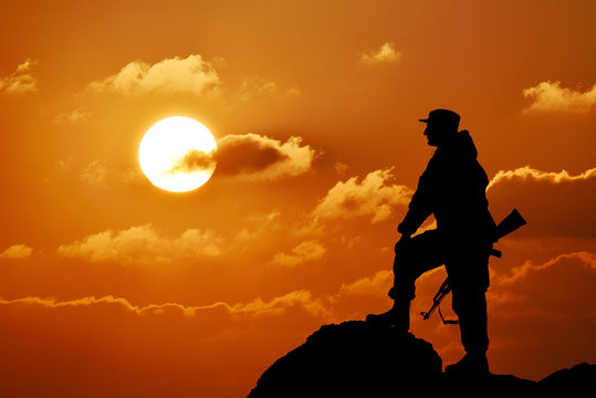 Silhouette of military soldier officer with weapons, sunset