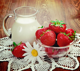 Rustic still life. Milk and strawberries on a table with flowers