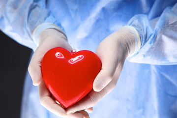 Female doctor with stethoscope holding heart, isolated on white