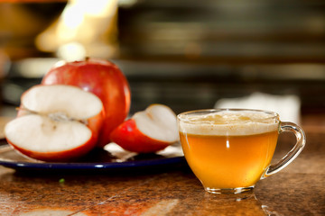 Glass cup of freshly juiced apple on kitchen counter next to pla