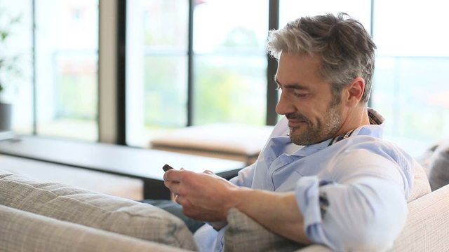 Mature man sending message with smartphone