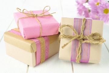 Gift boxes with brown and pink paper wrap on white wood