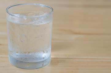glass of water with ice on wooden table