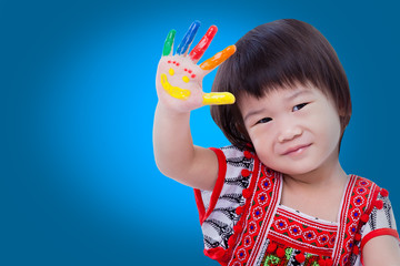 Adorable little asian (thai) girl painting her palm, on blue bac