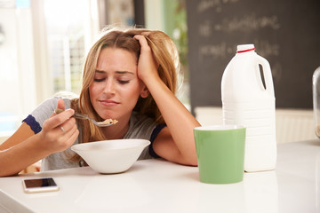 Young Woman Eating Breakfast Whilst Using Mobile Phone