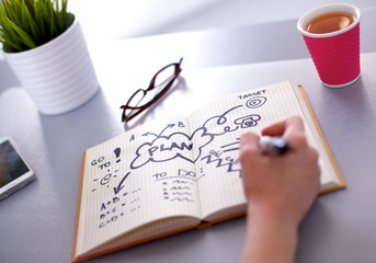 Young woman writes to diary on a white table