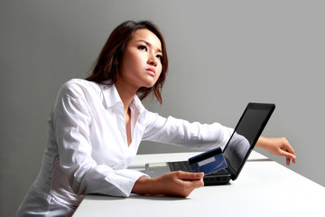 Young businesswoman thinking in front of laptop