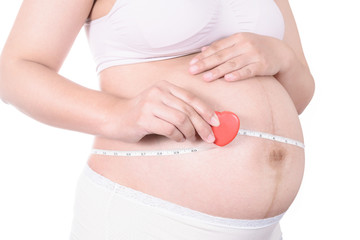 Pregnant woman measuring her stomach with tape measure