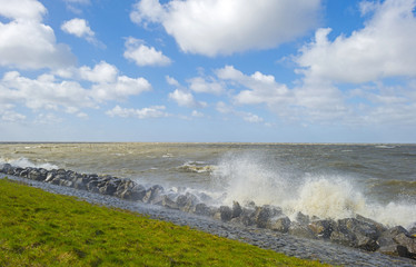 Storm raging over a lake along a dike in spring