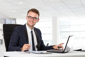 Young businessman posing in front of laptop