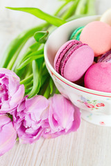 colorful macarons and tulips on wooden surface