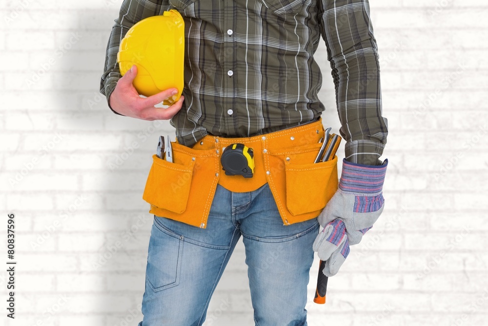 Poster manual worker wearing tool belt while holding hammer and helmet