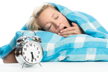 Blonde Frau liegt im Bett und gähnt
