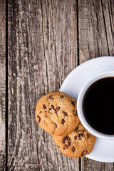 Cup of coffee with cookies on a wooden table.