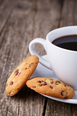 Cup of coffee with cookies on a wooden table.