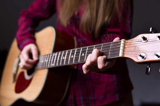 woman's hands playing acoustic guitar, close up, finger position