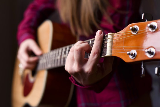 woman's hands playing acoustic guitar, close up, finger position