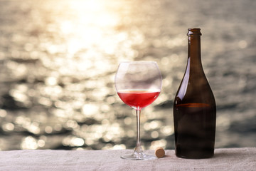 Bottle and glass of red wine on the table against the sea