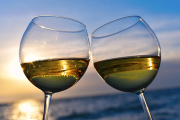 Romantic glass of wine sitting on the beach at colorful sunset