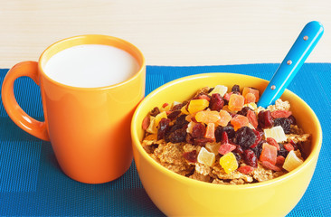 Bowl of cereal with dried fruits and a mug of milk