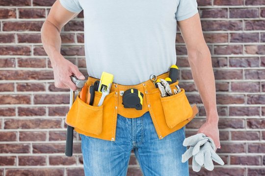 Composite image of technician holding gloves and hammer