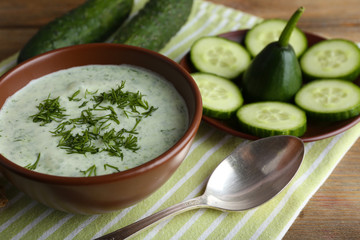 Cucumber soup in bowl on rustic wooden table background