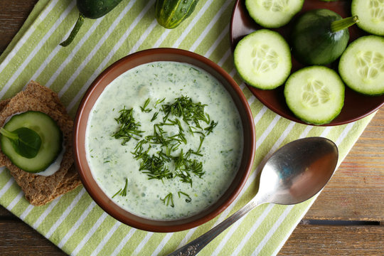 Cucumber soup in bowl on rustic wooden table background
