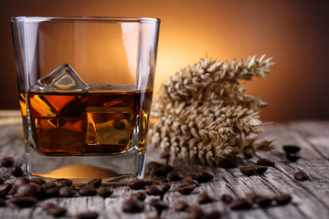 Glass of whiskey with ice and wheat on a wooden table. © garry_images