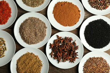 Different spices on plates, on old wooden table