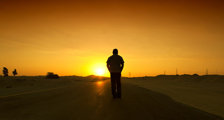 Fototapeta na wymiar Man walking on the Dubai desert road
