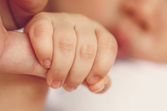 Newborn baby holding mother's hand, image with shallow depth of