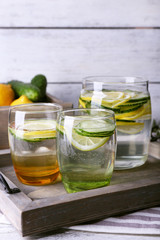 Fresh water with lemon and cucumber in glassware in wooden