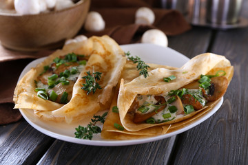 Pancakes with creamy mushrooms in plate on wooden table,