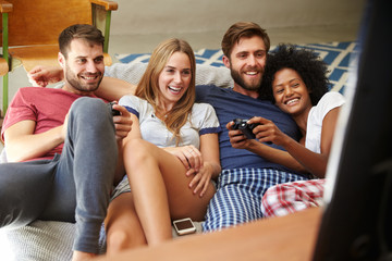 Group Of Friends Wearing Pajamas Playing Video Game Together